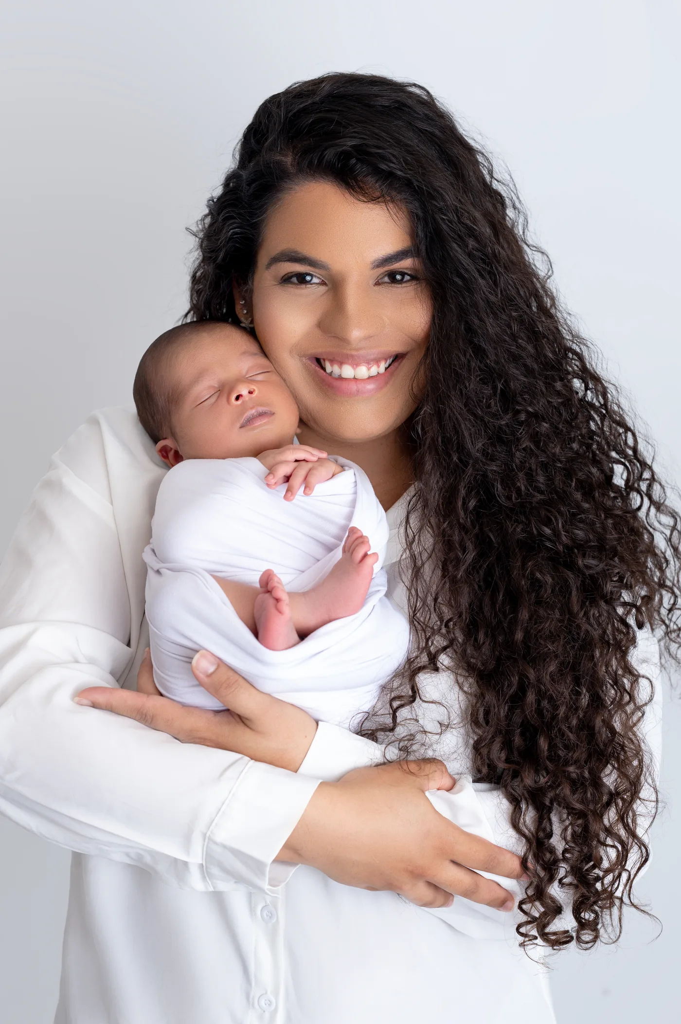 Mãe sorrindo com o recém-nascido encostado no rosto