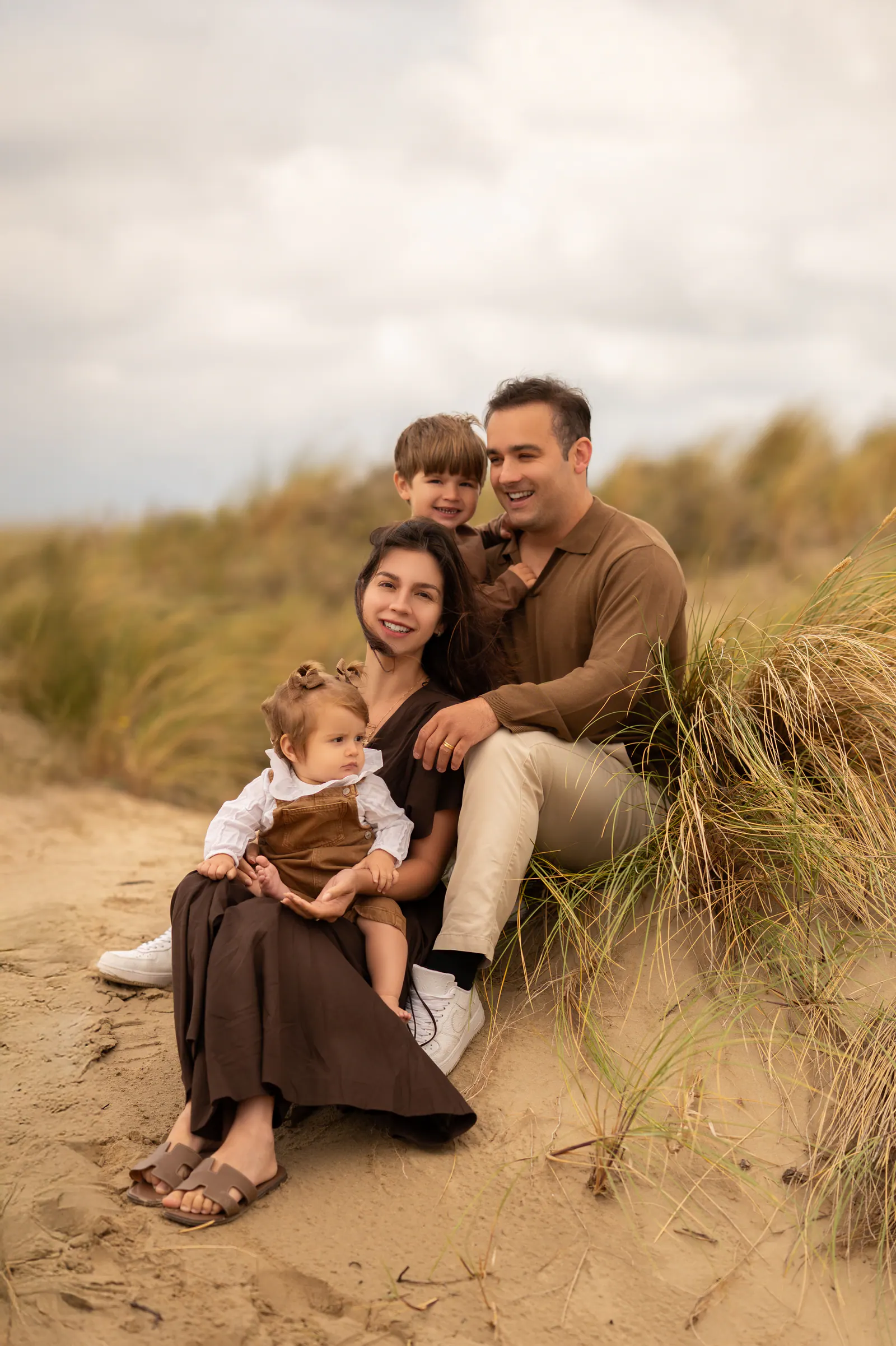 Família sentada na areia entre a vegetação das dunas